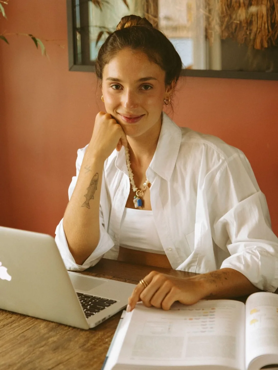 Beatriz à mesa, com notebook e livro, em sua foto original